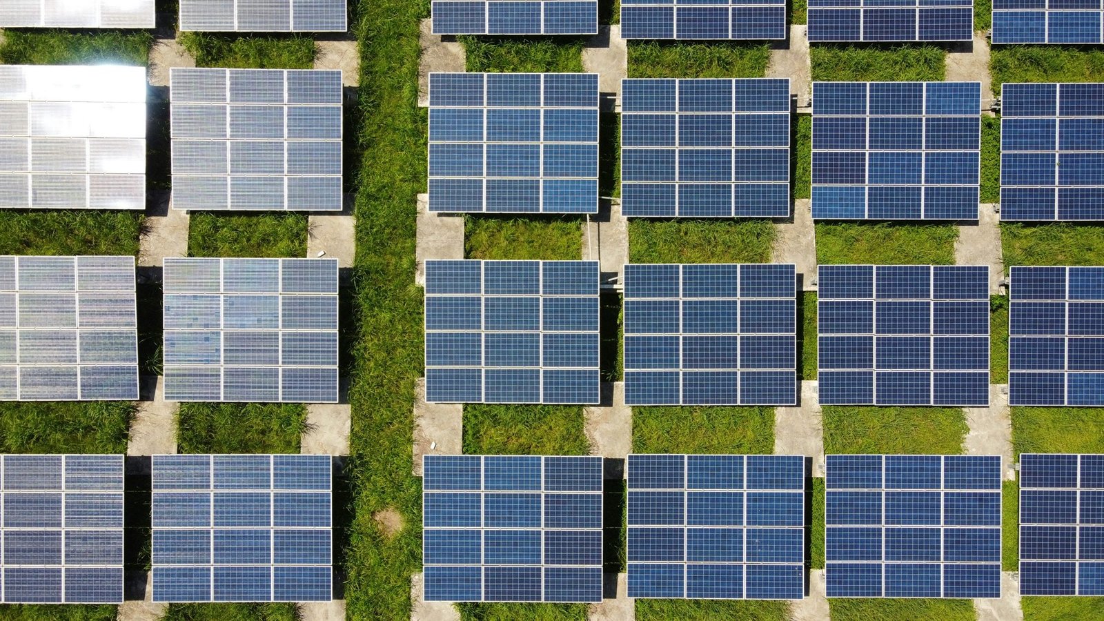 Vista aérea de una granja solar entre franjas de césped verde