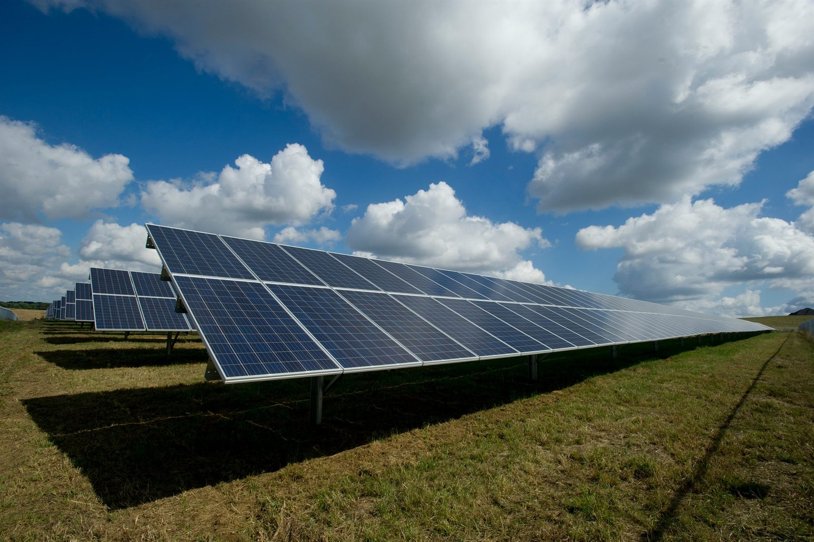 Hilera de paneles solares bajo un cielo azul con nubes