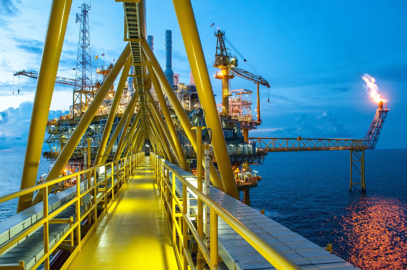 Pasarela de una plataforma petrolera iluminada al anochecer